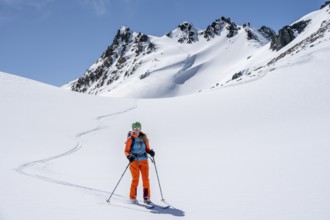Ski tourer on the descent, minimalist winter landscape, white snow and dark mountains on the