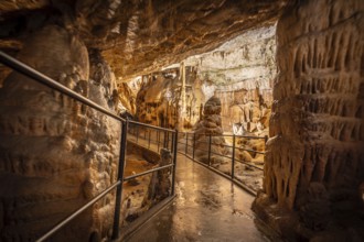 Tourists enjoying a guided tour walking on the footpath inside the famous postojna cave, a natural