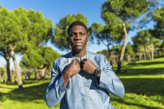 Young senegalese man wearing traditional dashiki attire, posing in a serene park setting,