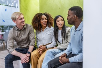 Four colleagues from diverse backgrounds are having a productive discussion in a modern coworking