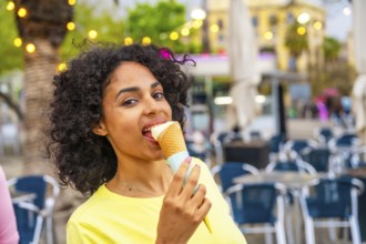 Close-up portrait of a latin woman biting an ice cream cone in the city
