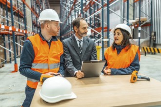 Warehouse workers and manager discussing logistics using a clipboard in a large distribution center