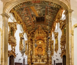 Interior and altar of a historic baroque church richly decorated with gold leaf ornaments and