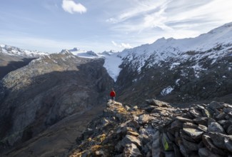 Mountaineer standing on a rock, surrounded by an impressive mountain landscape with snow-covered