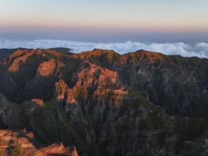 Aerial drone view of Pico do Arieiro and mountains over clouds on sunset. Above Pico Ruivo, Madeira