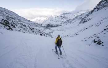 Skiers skiing downhill in a snow-covered mountain landscape in the Madritschtal valley, Ortler