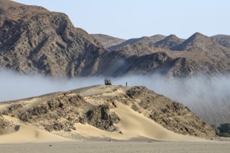 Safari vehicle on a hill in the Hoanib dry river, coastal fog, Kaokoveld, Kunene Region, Namibia,