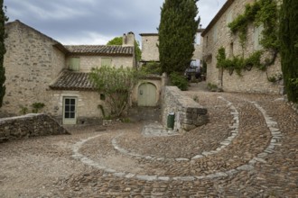 Winding path along old houses up a slope through La Roque-sur-Cèze, Département Gard, Occitania