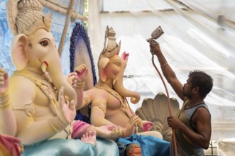 An artisan decorates an idol of the elephant-headed Hindu deity Ganesha at a workshop ahead of the