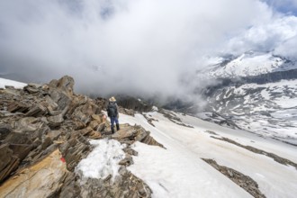 Mountaineer on a rocky ridge with snow, descent from the summit of Schönbichler Horn, view of