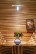Flower arrangement on an altar table in a modern, wood-panelled interior with cross, Penken,