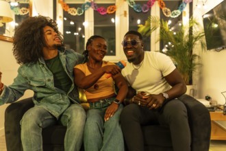 Multi-ethnic friends sharing karaoke singing together on the sofa