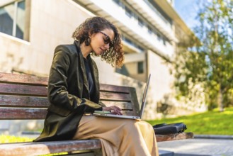 Profile of a beauty young arab businesswoman in casual clothes and sunglasses working with laptop