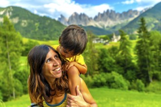 Mother carrying her son on her shoulders, enjoying a sunny day in the italian dolomites with the