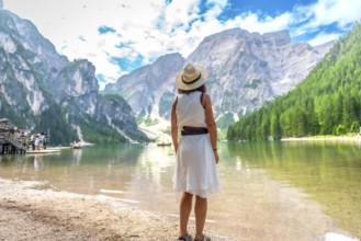 Woman admiring the stunning landscape of lake braies, surrounded by majestic mountains and lush