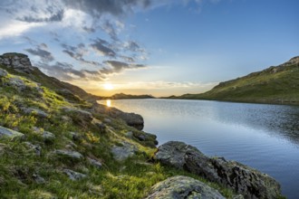 Calm lake with mountains and rocks at sunrise, clouds in the sky, Tyrol, Austria, Europe