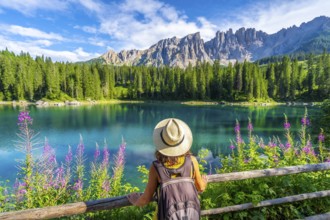 Female tourist admiring the stunning turquoise waters of lake carezza with the latemar mountain
