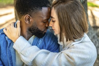 Close-up of two multi-ethnic lovers embraced on a park