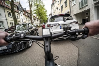 Cycling in the city, city centre street, residential street, 30 km/h zone, traffic with parked cars