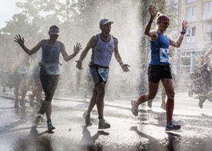 The participants of the Berlin Marathon are cooled down with a water shower in the Schöneberg