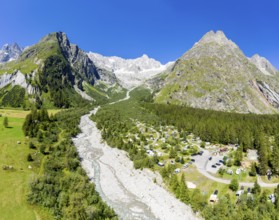 Panoramic aerial view of a campsite at a glacial river, mountain range with glacies in the back, La