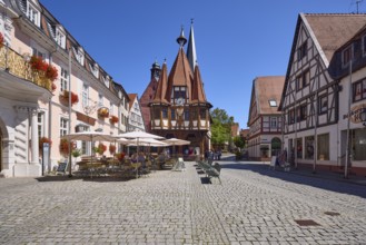 Historic town hall with outdoor area of the confectionery and café Leyhausen under a cloudless blue