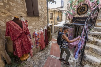 Women's clothing, woman, 62 y., in front of Boutique Alkimia in the mountain village Èze Village on