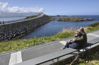 Couple sitting on a bench on the Atlantic Road in Norway