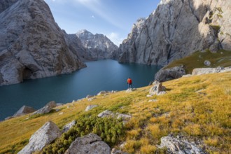 Tourist at the blue mountain lake between rocky steep mountain peaks, Kol Suu Lake, Sary Beles