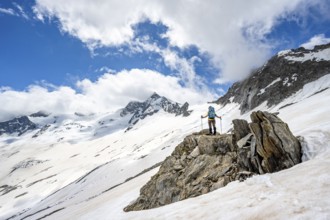 Mountaineer on a rock between snow, descent from the summit of Schönbichler Horn, view of