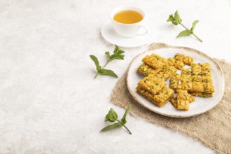 Traditional iranian dessert sohan with cup of green tea on a gray concrete background and linen