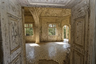 Dilapidated room with decorated tiles, open windows and arched doorway, showing a ruined structure
