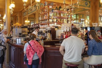 Cosy café with people at the counter, warm wood panelling and glowing lamps, Paris