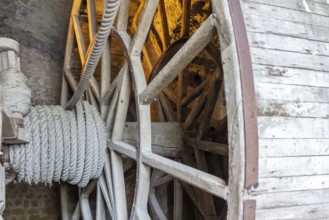 Close-up of a wooden wheel with rope under golden light, Le Mont-Saint-Michel