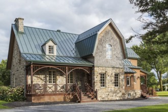 Old 1826 Canadiana cottage style fieldstone house facade with vertical wood plank cladding, cedar