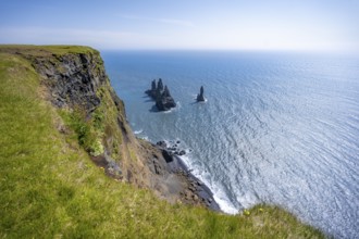 Steep coast, view from steep cliff to the rocks Reynisdrangar in the water, at Reynisfjara beach,