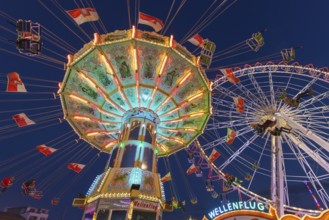 A funfair at dusk with illuminated chain carousel and Ferris wheel, Europa Rad, rides, wave flight,