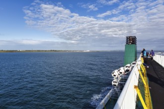 Passengers on a ferry between Ireland and Wales, view of the sea and coastline, spring clouds,