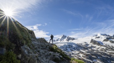 Mountaineer in front of high alpine mountain landscape with sun star, summit of Aiguille de