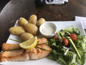 Grilled salmon with potatoes and fresh salad, served on a wooden table in rustic style, Norwegian