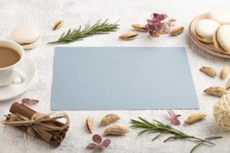 Blue paper sheet mockup with cup of coffee, almonds and macaroons on gray concrete background.