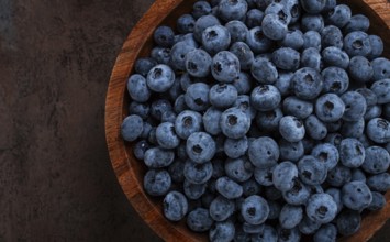 Fresh blueberries, in a wooden bowl, on the table, top view, close-up, no people
