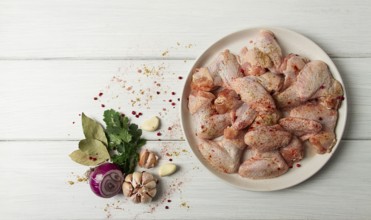 Frische, rohe Hähnchenflügel, mit Gewürzen, auf einem weißen Holztisch