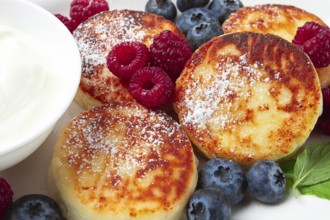 Breakfast, cottage cheese cakes, with fresh berries, and sour cream, top view, close-up, no people