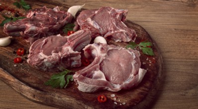 Raw calf meat, meat on the bone, meat for barbecue, cutting board, with spices and herbs, top view
