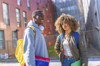 Cool multiethnic students outside the university holding notebooks and carrying rucksack