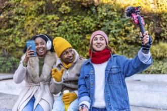 Three young content creators are filming a video blog outdoors in a winter city setting, using a