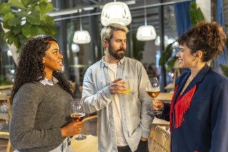 Diverse friends chatting and drinking standing together in a night bar terrace