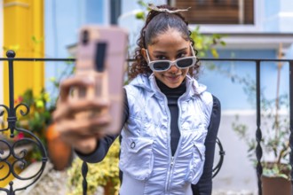Cool urban african woman taking selfie smiling next to colorful house