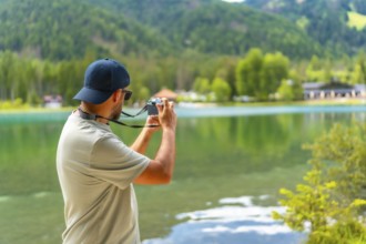 Tourist taking pictures of lake dobbiaco in the dolomites during summer holidays, capturing the